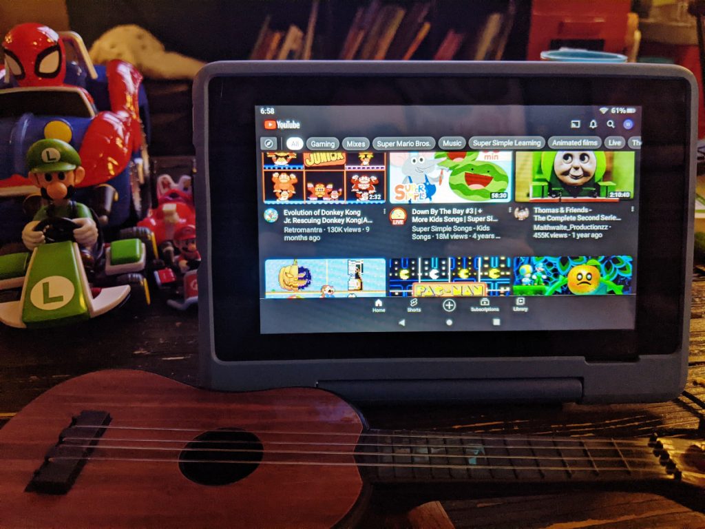 An Amazon Fire HD 7 Kids Pro tablet running YouTube, sitting beside toys
